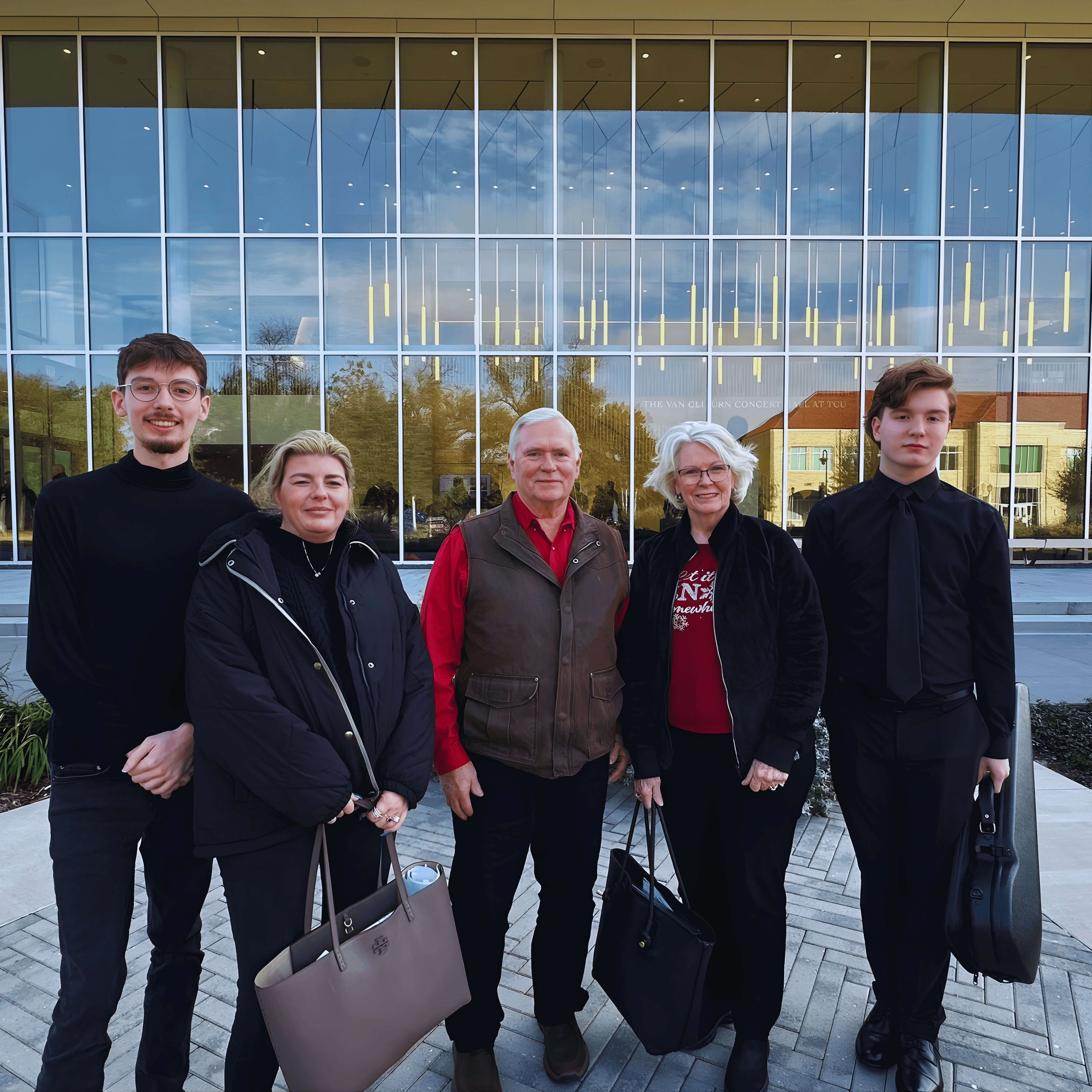 Family of five smiling in front of the Van Cliburn Concert Hall at TCU.