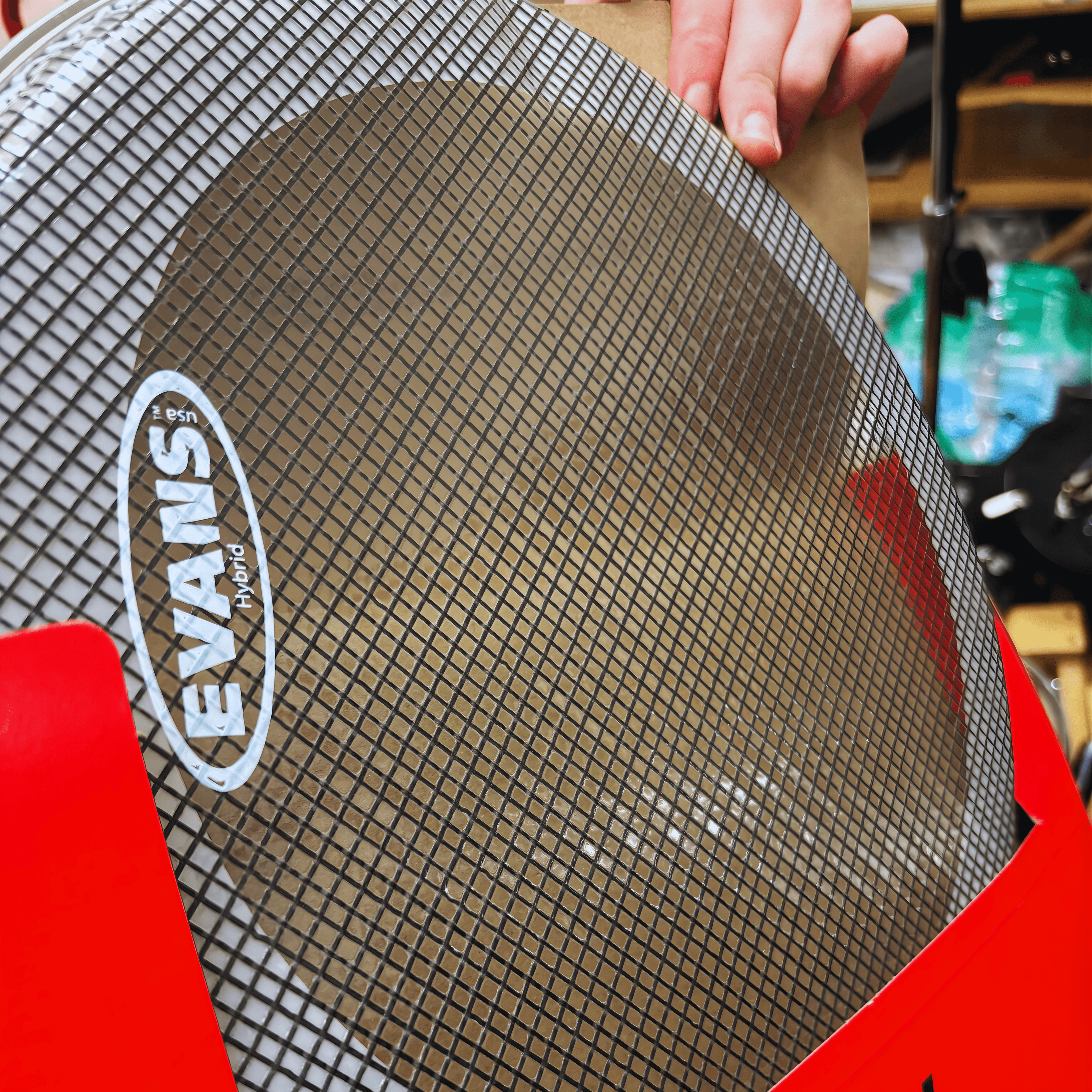Evans Hybrid mesh drumhead with a black grid pattern, partially in red packaging.